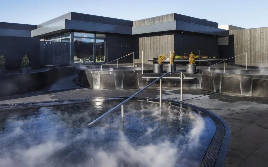 Ein Badehaus mit dampfenden Becken, umgeben von Schnee im Westen Islands