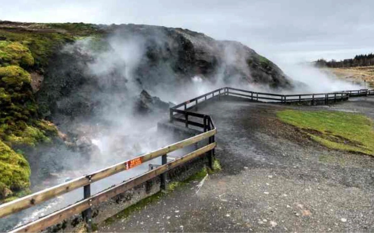 Steam drifting across the surface of a warm stream between mossy banks